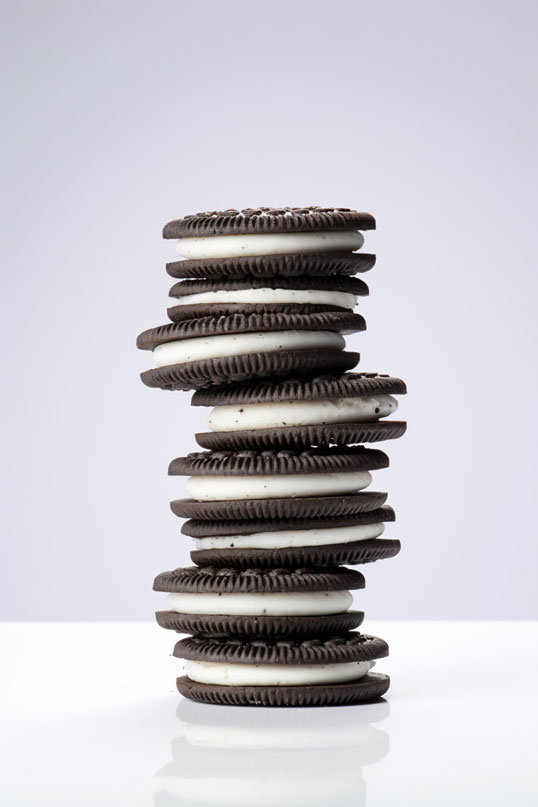 Torre en quilibrio de galletas tipo oreo sobre una mesa blanca.